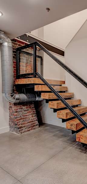 A staircase with a metal railing and wooden steps leads up to a second floor.