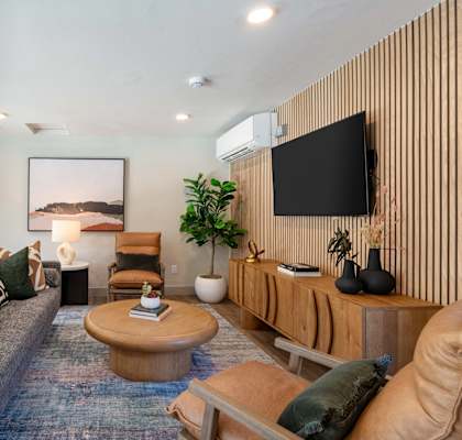 A living room with a grey couch, a wooden coffee table, and a large painting on the wall.
