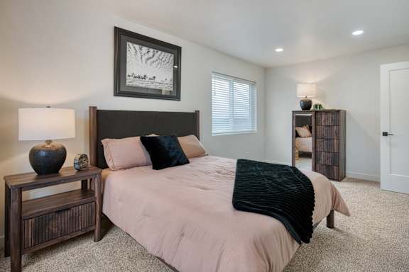 A bedroom with a bed, nightstand, and a picture on the wall.