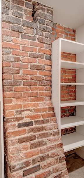A white shelving unit is built into a brick wall.