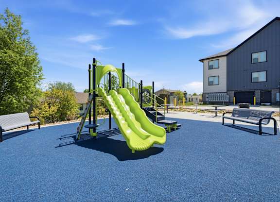 A playground with a green slide and a blue surface.