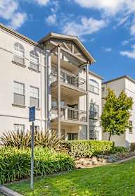 A modern apartment building with a well-maintained lawn and walkway.