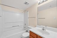 A white bathroom with a toilet, sink, and shower.