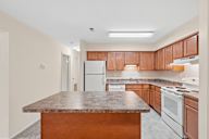 A kitchen with a granite countertop and wooden cabinets.