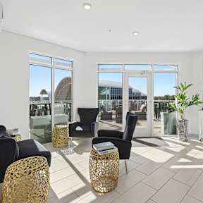 Rooftop indoor lounge with seating, large windows, and access to the outdoor terrace
