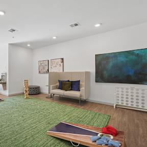 Game room with cornhole boards, Connect Four, and lounge seating at The Constellation on King