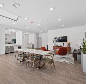 Resident lounge with sofa seating, dining table, kitchenette, and garage-style doors at The Constellation on King