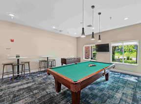 A room with a pool table and bar stools.