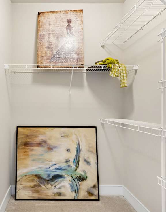 A room with a white wall and a painting on the floor.