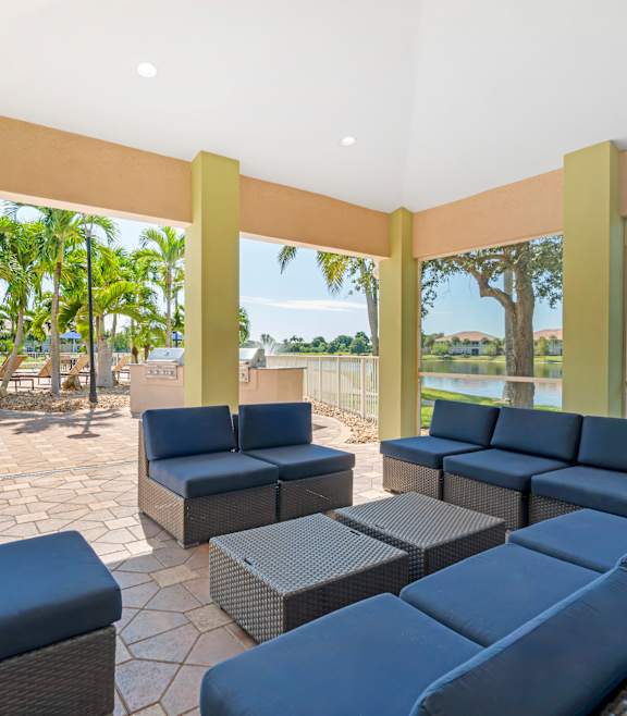 a patio with a table umbrella and chairs next to a pool at Bay Breeze Villas, Fort Myers, Florida
