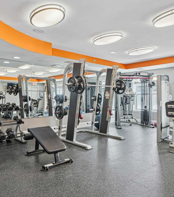 A gym with orange walls and a variety of exercise equipment.