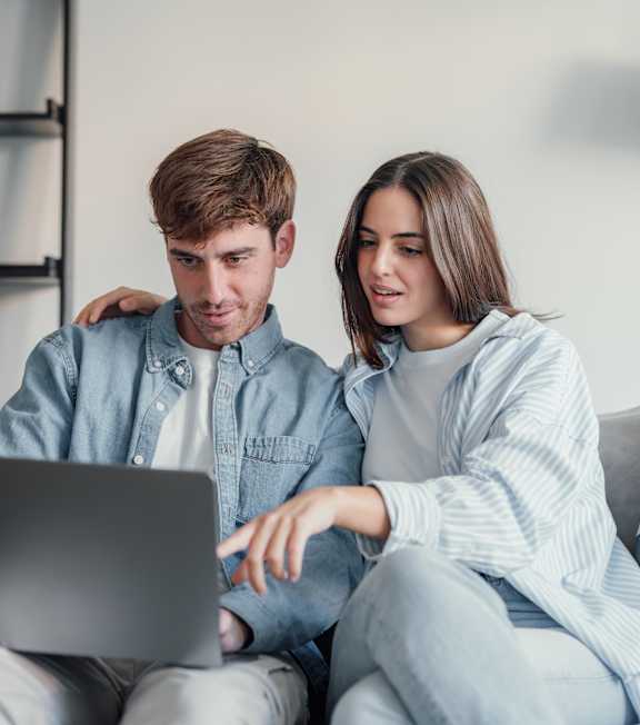 A man and woman sitting on a couch looking at a laptop. A man and woman sitting on a couch looking at a laptop. at Viridian Apartments LLC Apartments, Bowling Green