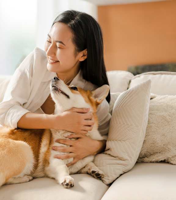 A woman is hugging a dog on a white couch.