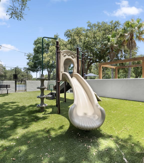 a playground with a slide and a swing set in a backyard