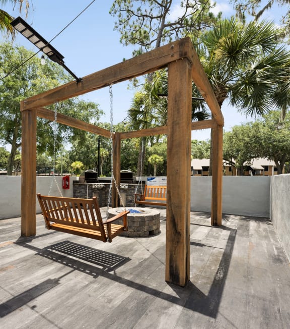 a swing bench in the backyard of a house