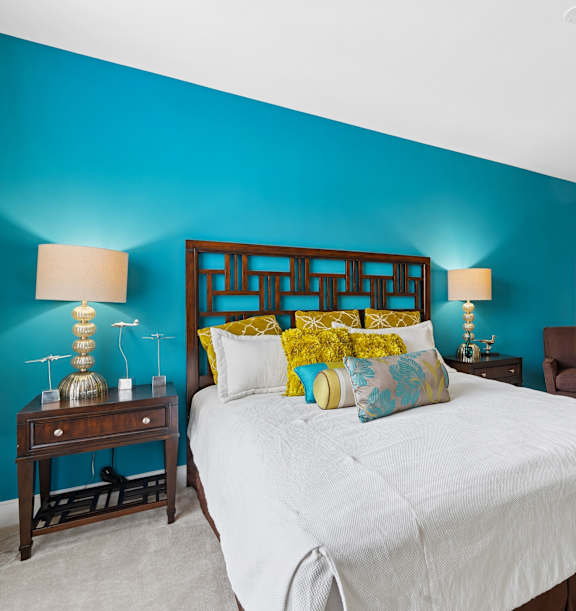 A bedroom with a white bed and a blue wall.