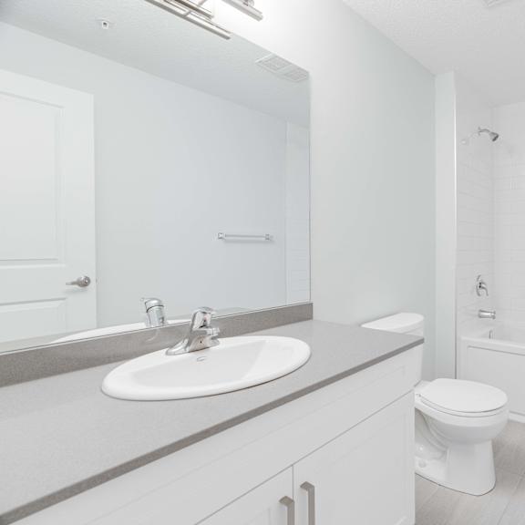 A white bathroom with a toilet, sink, and bathtub.