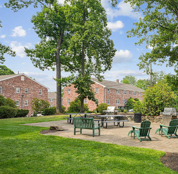 A green park area with a table and chairs in front of a building.