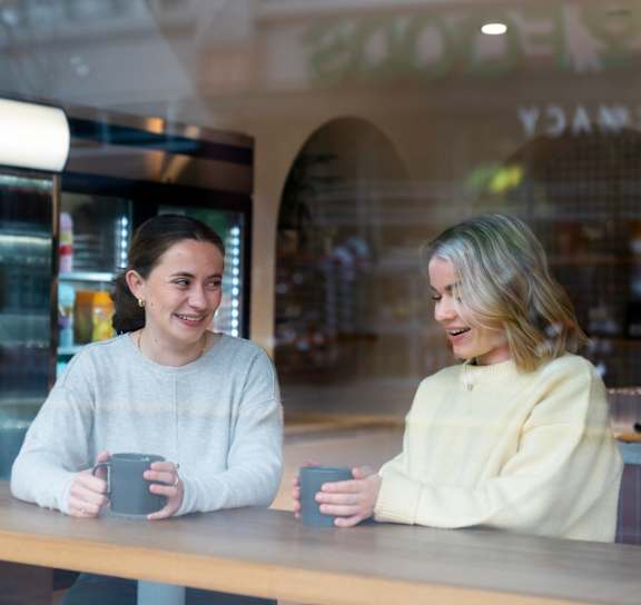 two men sitting on a bench in front of a store window