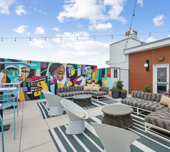 a patio with couches and chairs and a mural on the wall