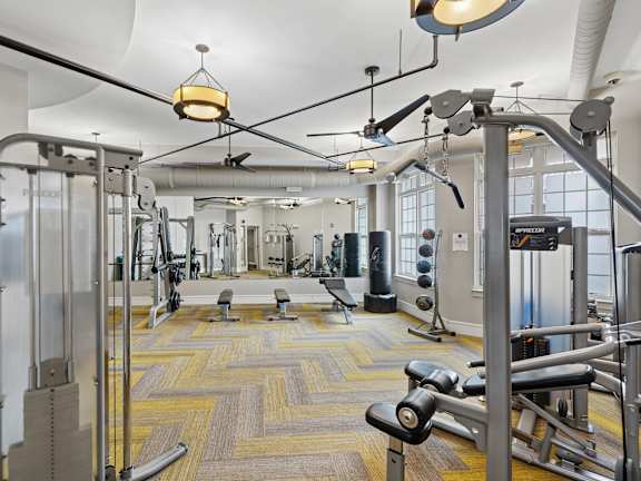 A gym with a variety of equipment including a weight bench, a squat rack, and a treadmill.
