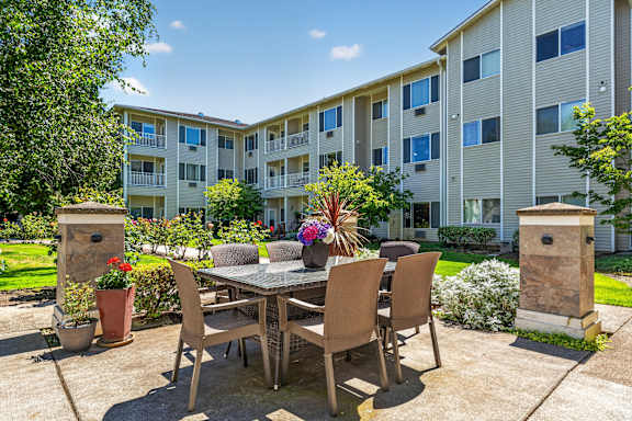 A patio with a table and chairs is surrounded by apartment buildings.