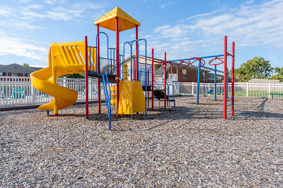 A playground with a yellow slide and red and blue structures.