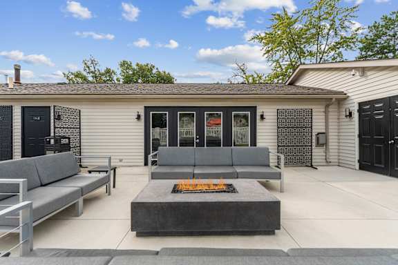 A modern house with a grey sofa and a fire pit in the front yard.