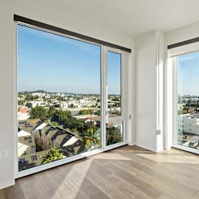 A modern living room with a dining table and a view of the city.