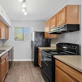 A kitchen with wooden cabinets and black appliances. at Emory Woods, Durham, 27713
