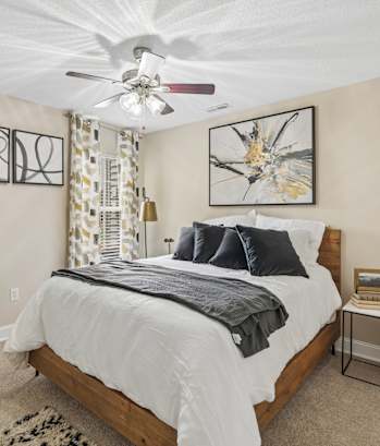 A bedroom with a large bed and a ceiling fan.