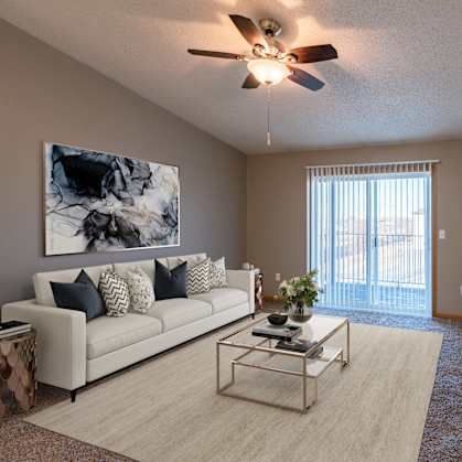 an open living room with a couch and a tv. Fargo, ND Sunwood Apartments