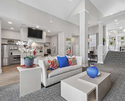 A modern living room with a white couch and a television mounted on the wall.