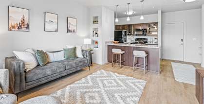 A living room with a grey couch and a bar area. at Wilmington Flats Apartments, Salt Lake City, UT, 84106
