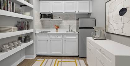 A kitchen with white cabinets and a grey backsplash.