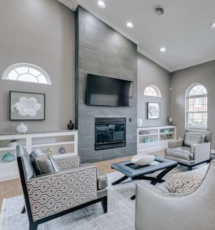 A modern living room with a stone fireplace and a grey sofa.