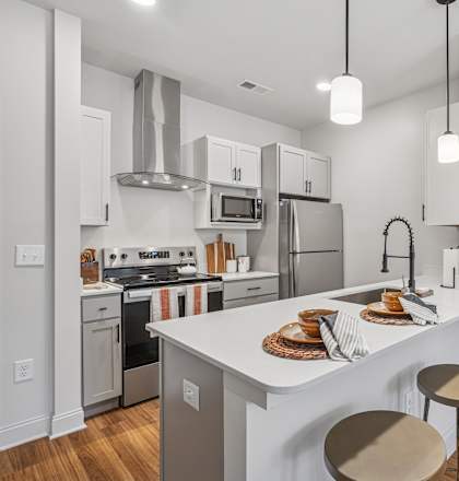 A modern kitchen with a white island and stools.
