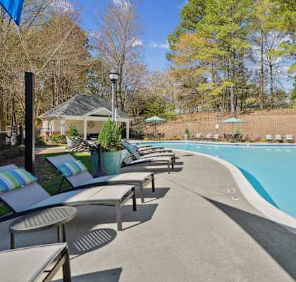 A pool surrounded by trees and a gazebo.