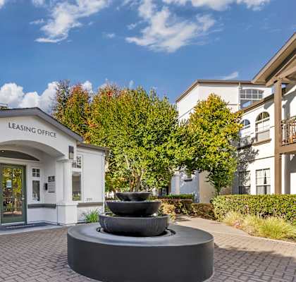 A building with a fountain in front of it and the words "Leasing Office" on the wall.
