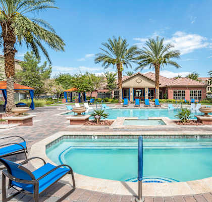 our resort style pool is surrounded by blue chairs and palm trees