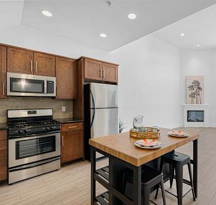 a kitchen with stainless steel appliances and a wooden table at The Social Apartments, North Hollywood, 91601