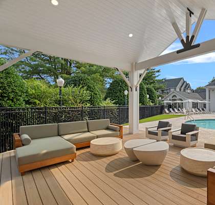 A patio with a white canopy and a pool in the background.