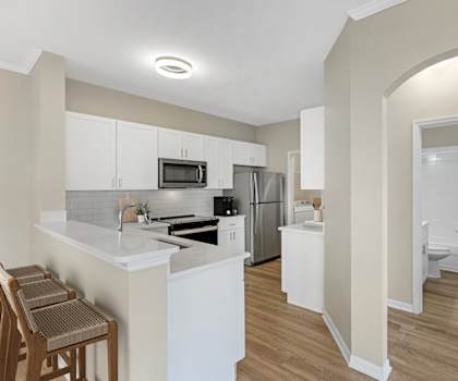 A kitchen with white cabinets and a countertop with a microwave and oven.