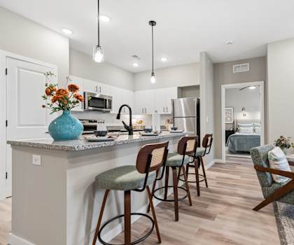 A kitchen with a bar and chairs.