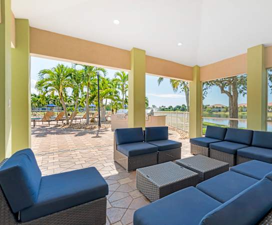 A patio with blue cushioned furniture and a view of a lake and trees.
