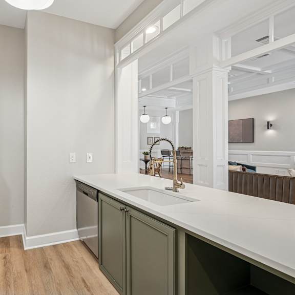 A kitchen with a refrigerator, sink, and cabinets.