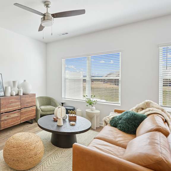 A living room with a brown leather couch, a wooden cabinet, a round table, and a floor lamp.