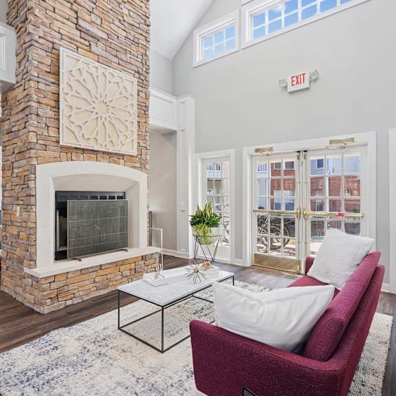 A living room with a red couch and a stone fireplace.