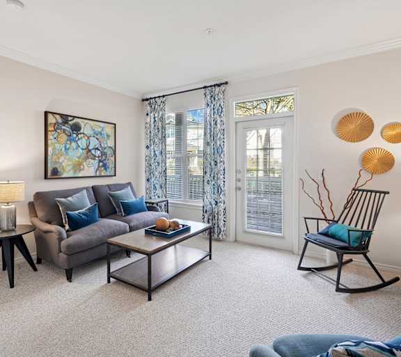 A living room with a grey couch, a coffee table, and a painting on the wall.