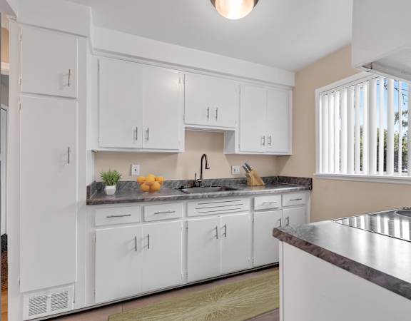 A kitchen with white cabinets and a marble countertop.